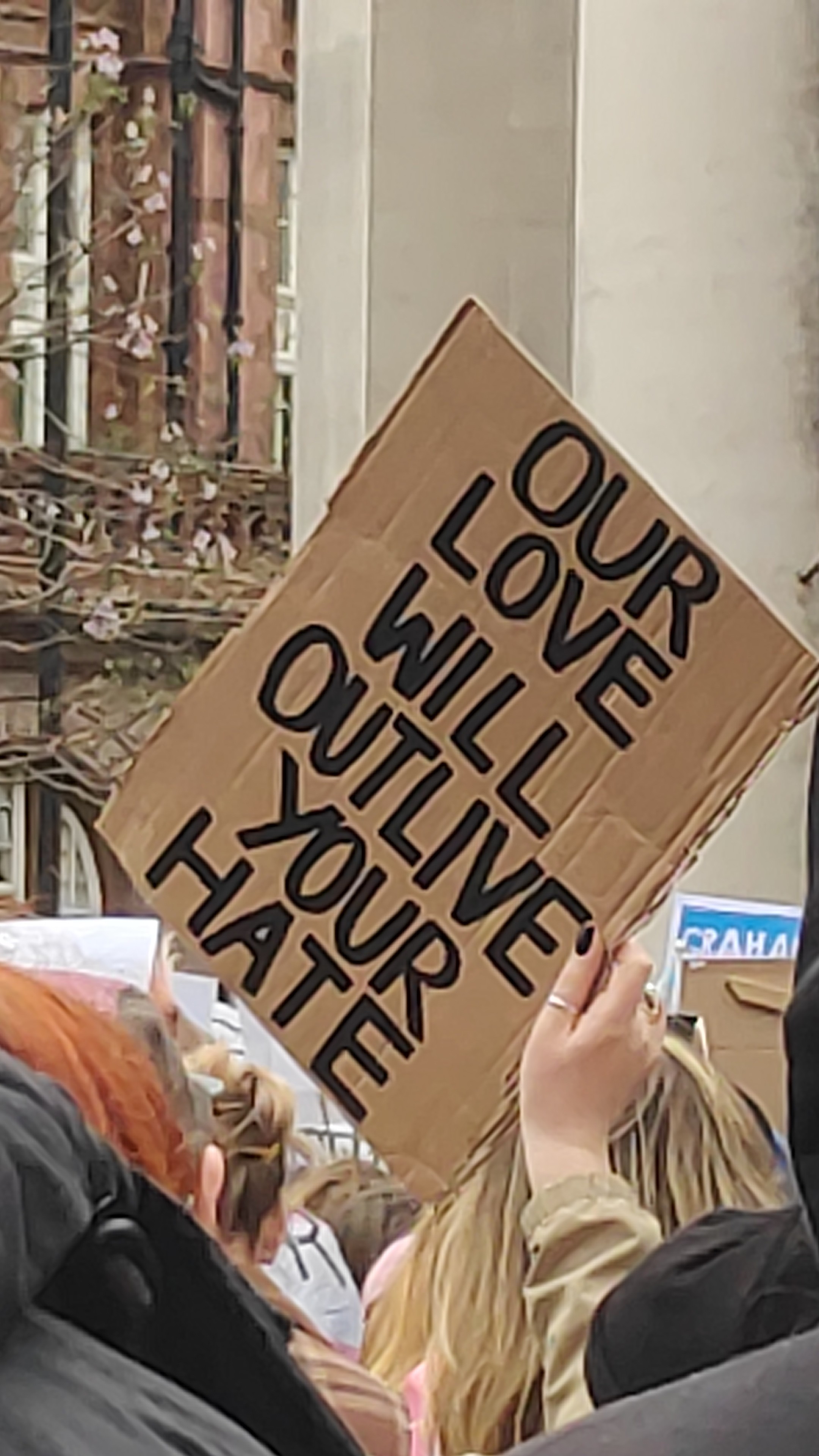"Our love will outlive your hate." On a piece of cardboard that's being held at a jaunty angle in a white person's hand.